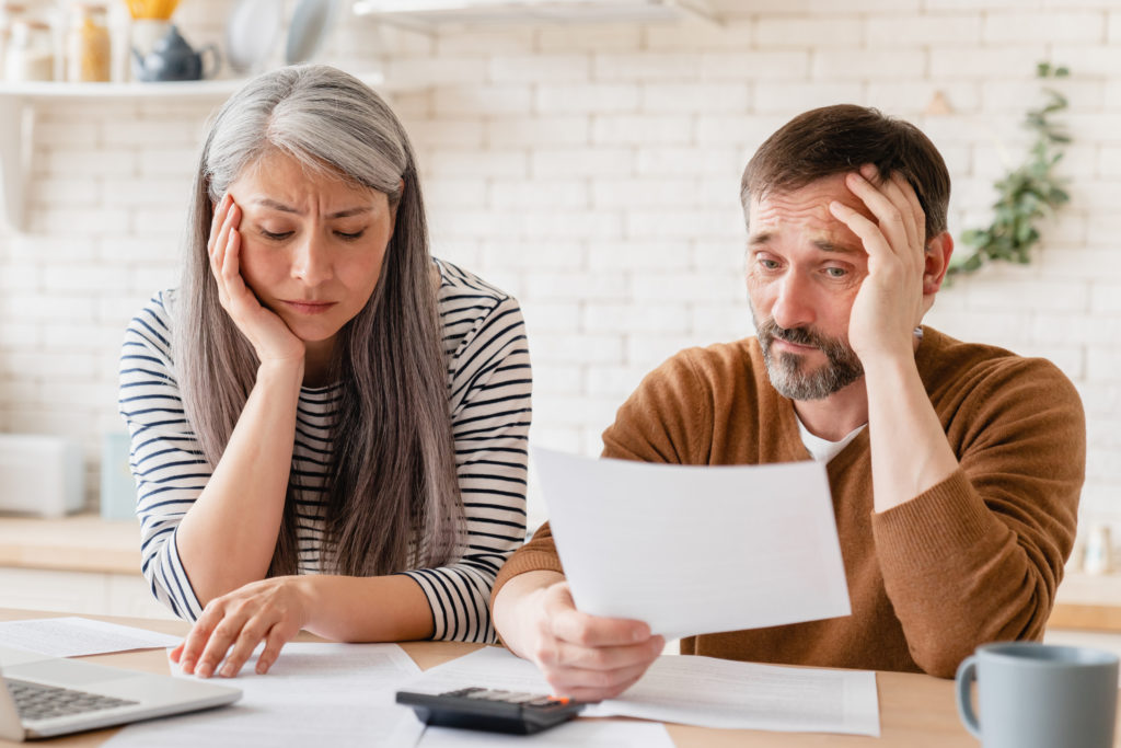 Sad couple who are looking through bills and worried about medical debt.